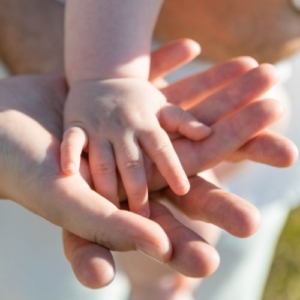 Photo d'une main d'enfant posée sur une main de femme posée sur une main d'homme